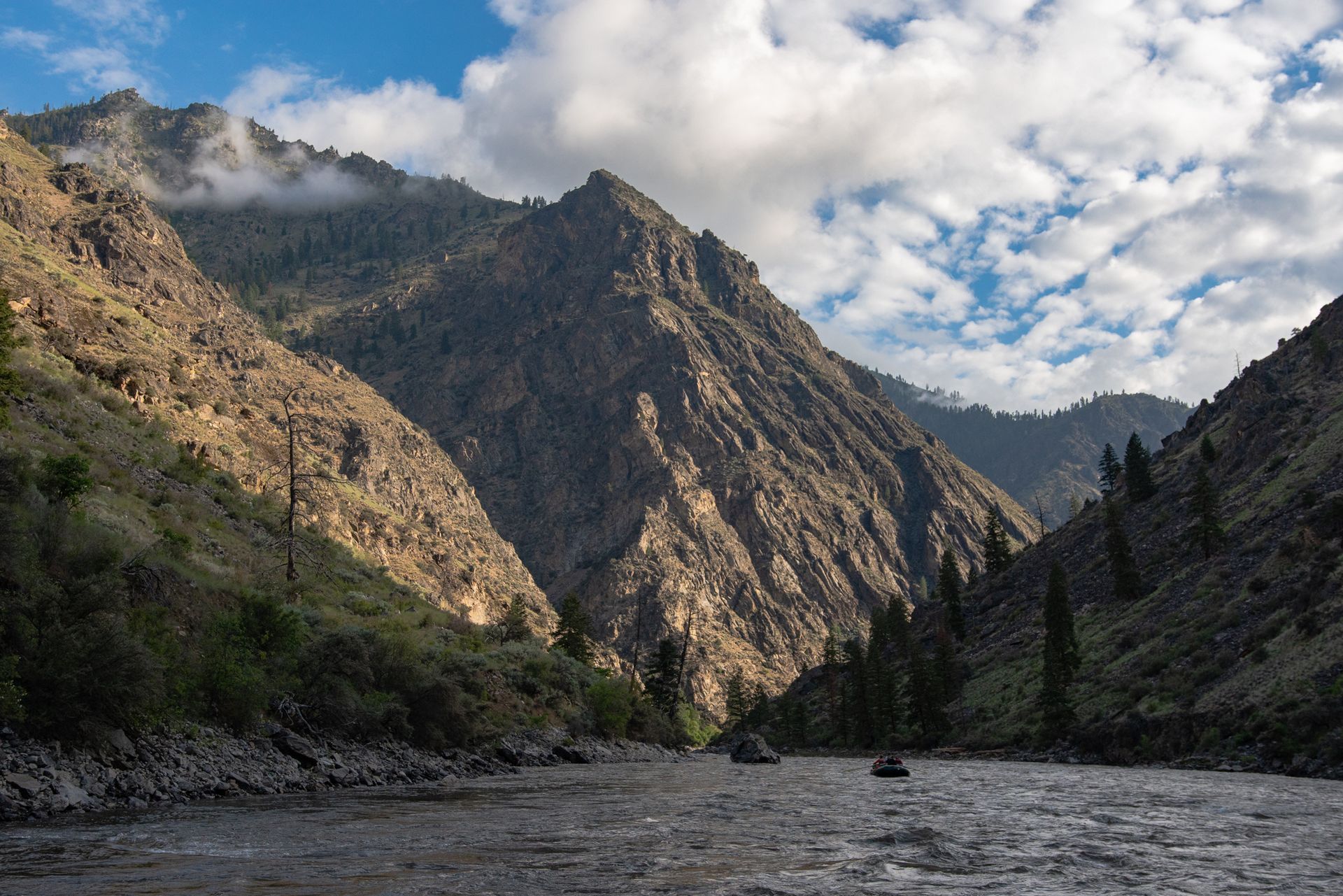A river flowing through a canyon with mountains in the background