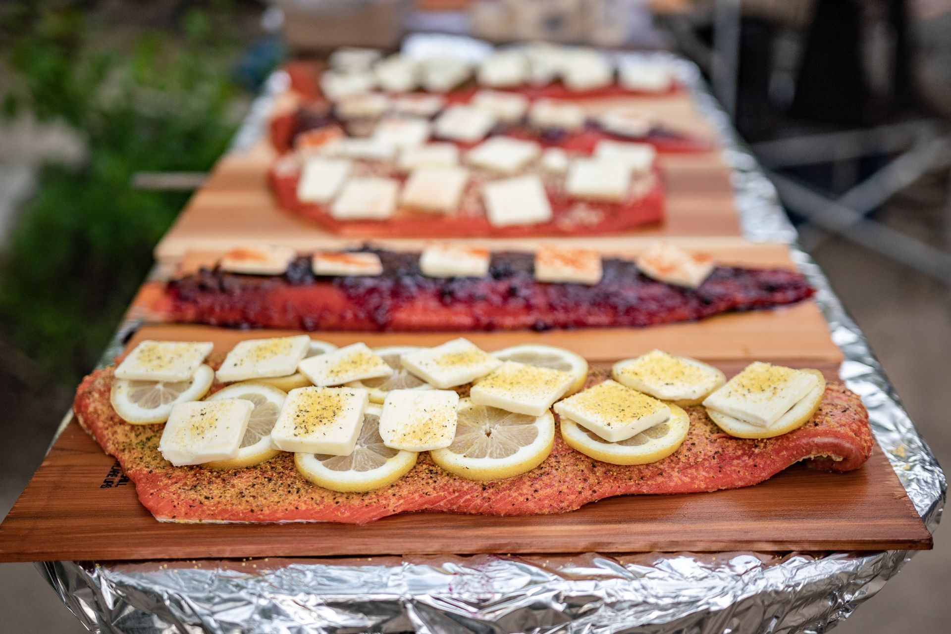 A wooden cutting board topped with a piece of salmon and lemon slices.