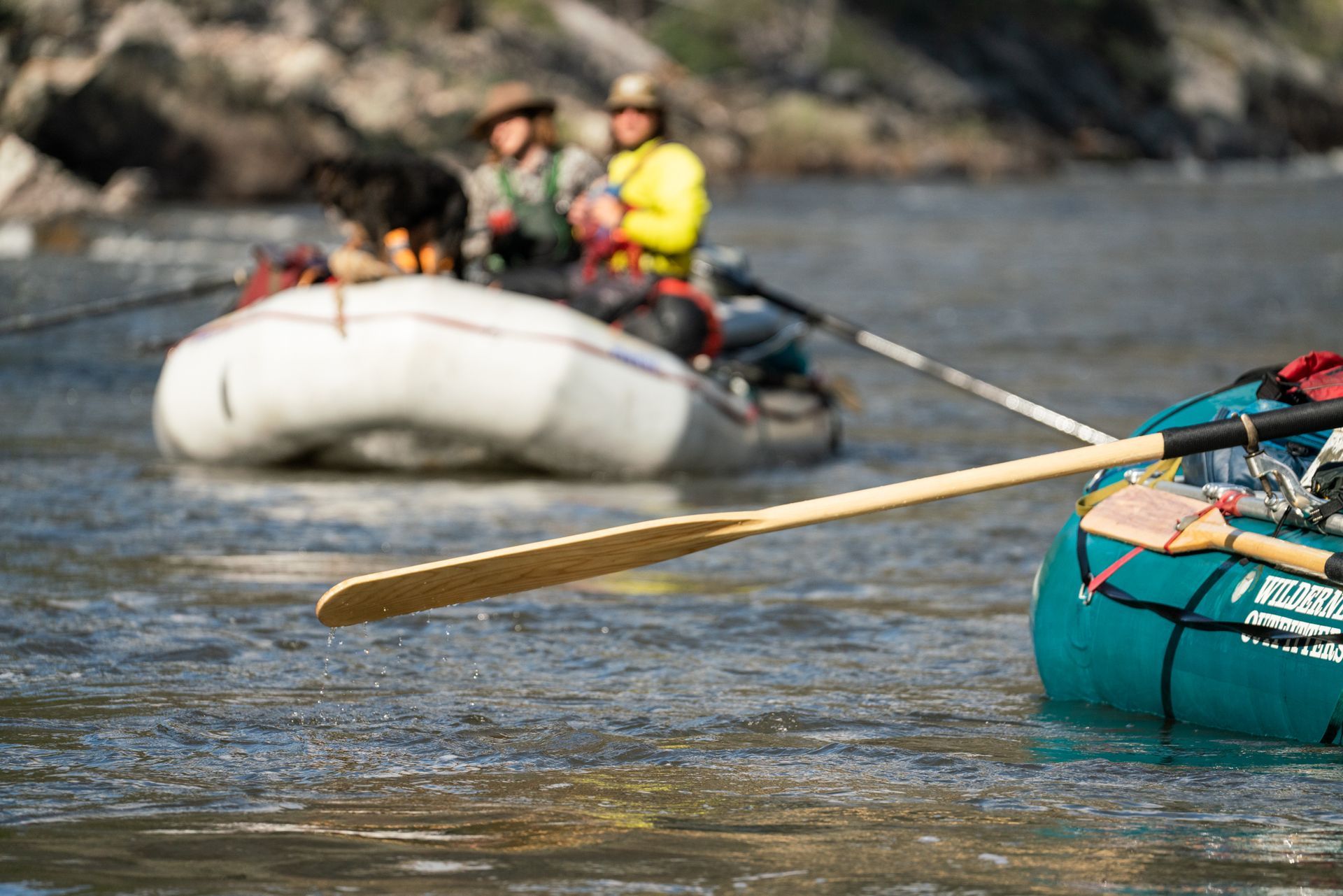 A group of people are rowing rafts down a river.