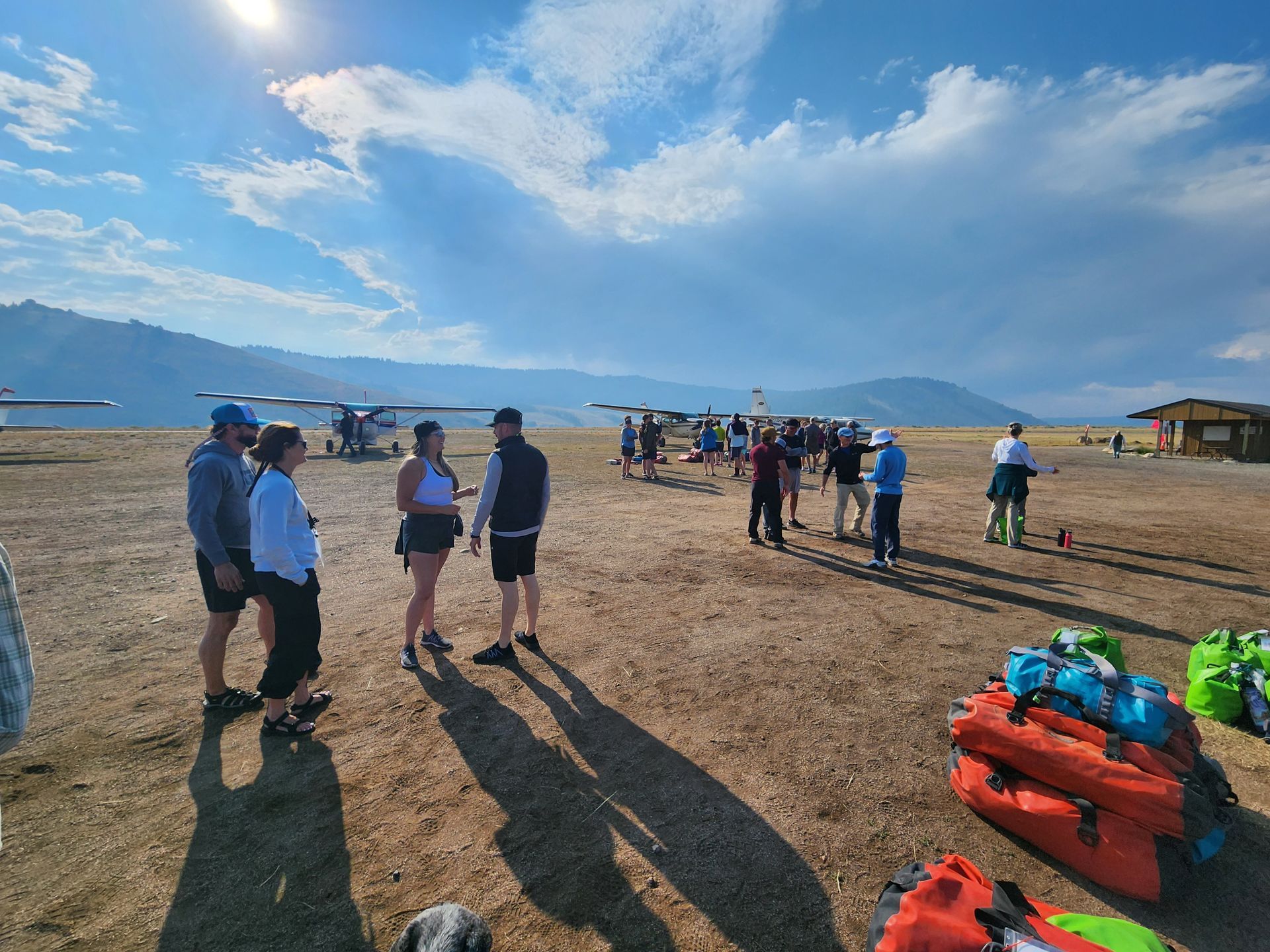 A group of people are standing on a dirt field in front of a plane.