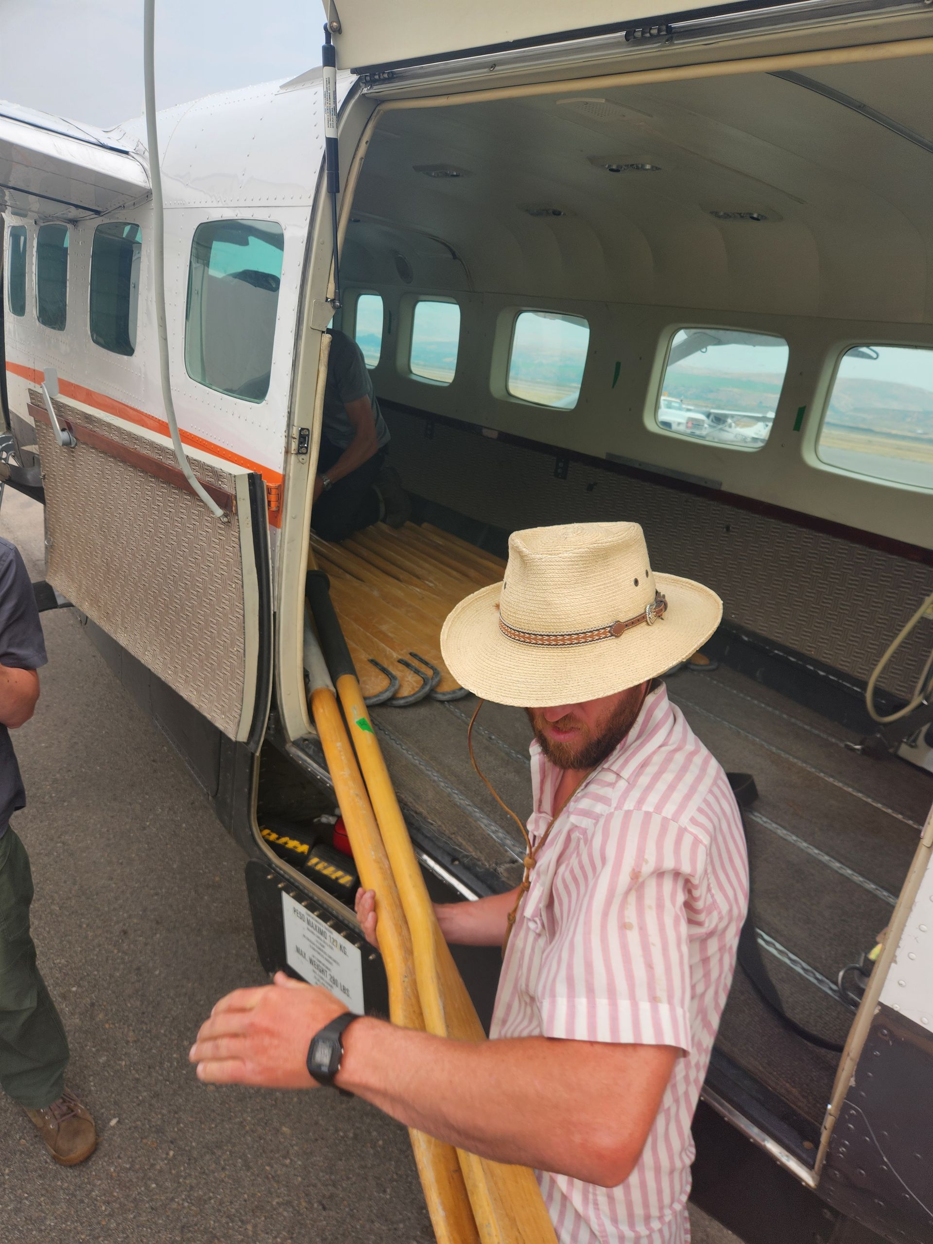 A man in a straw hat is loading a plane
