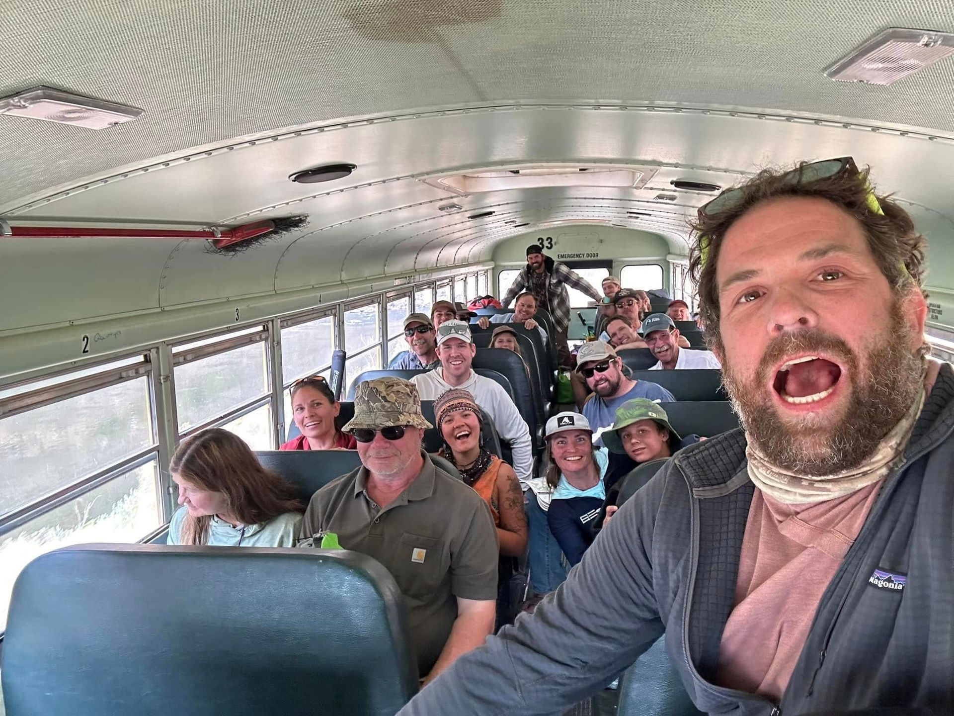 A man is taking a selfie on a bus with a group of people.