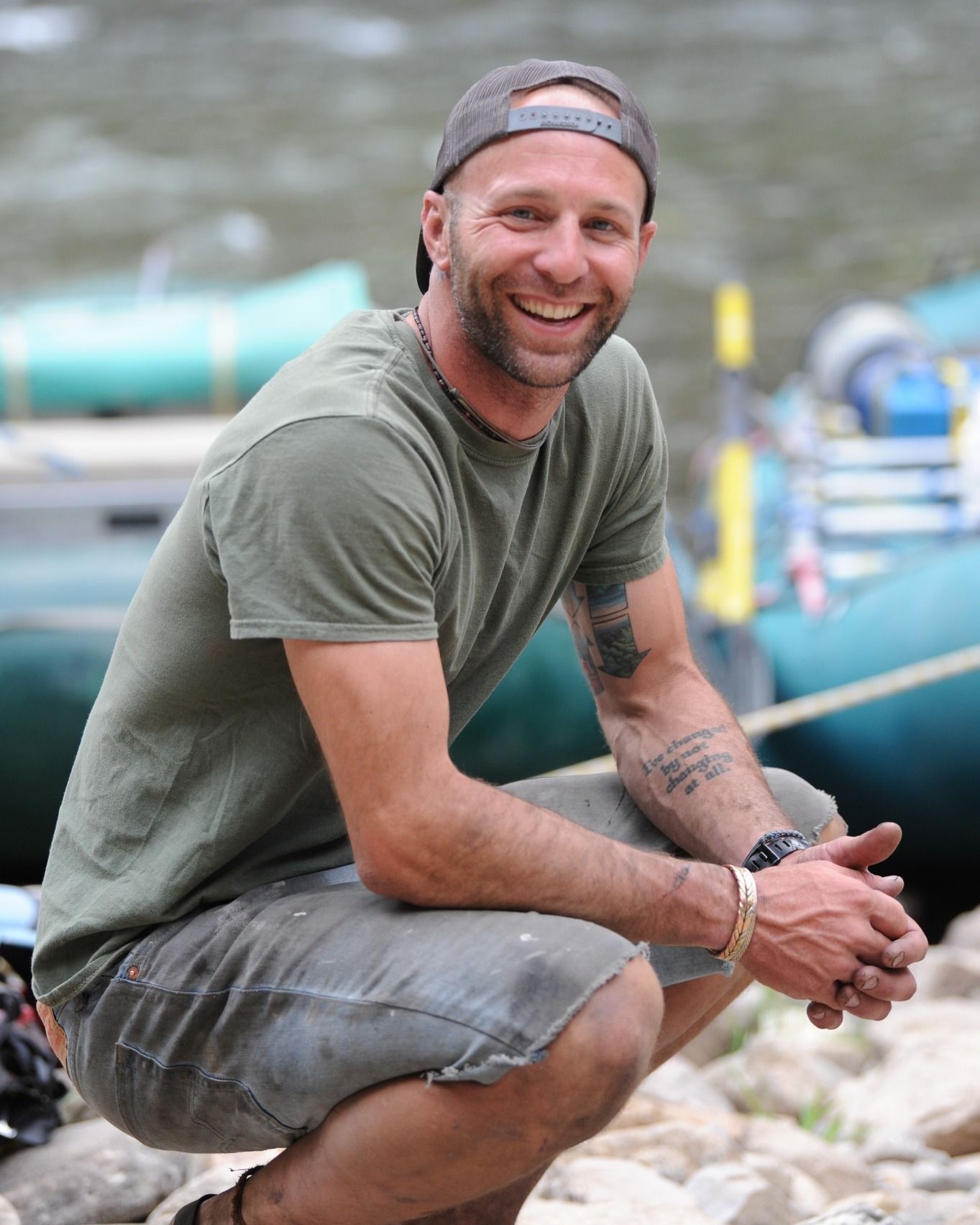 A man in a green shirt is squatting down and smiling