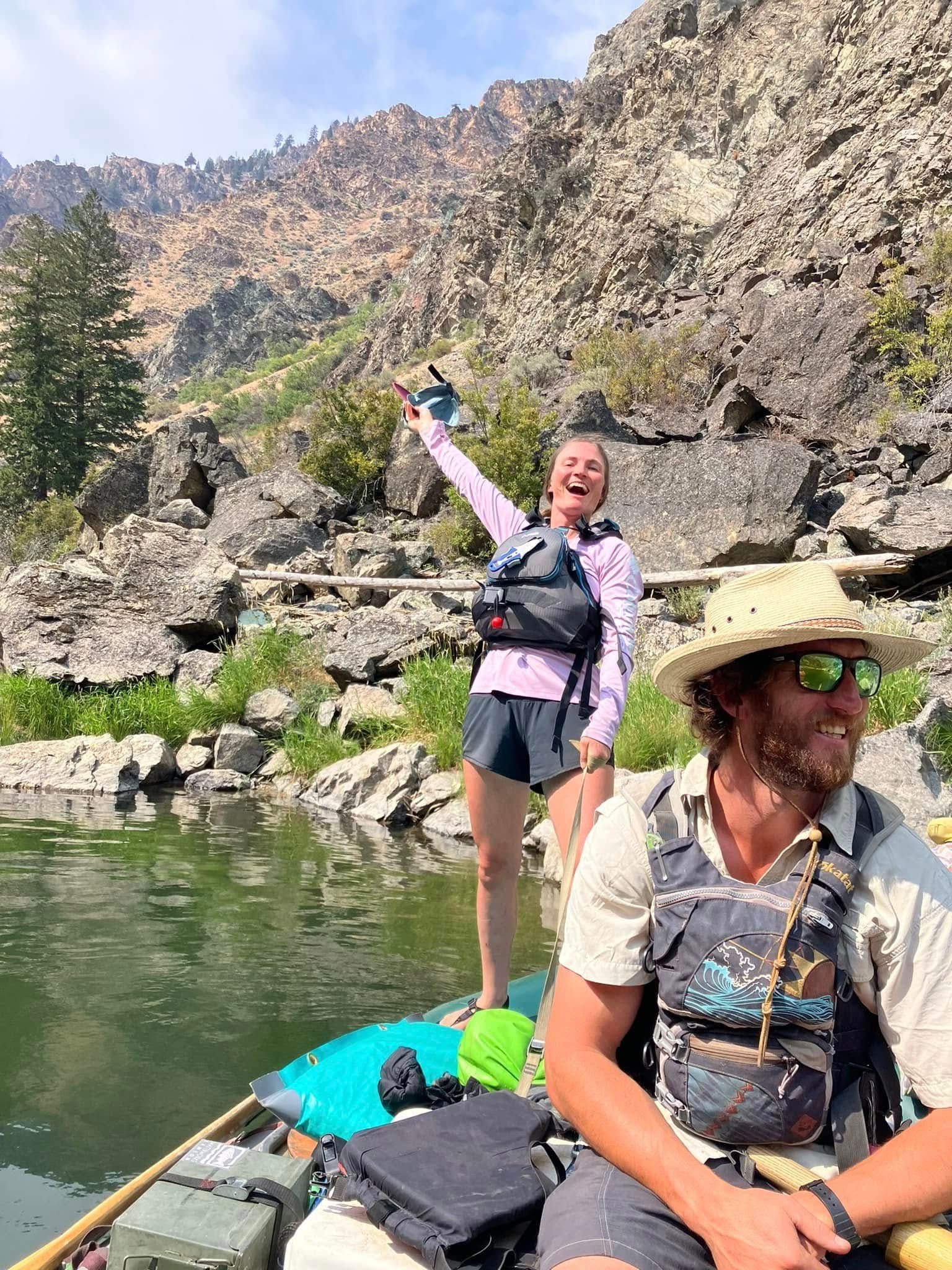 A man and a woman are sitting in a boat on a river.
