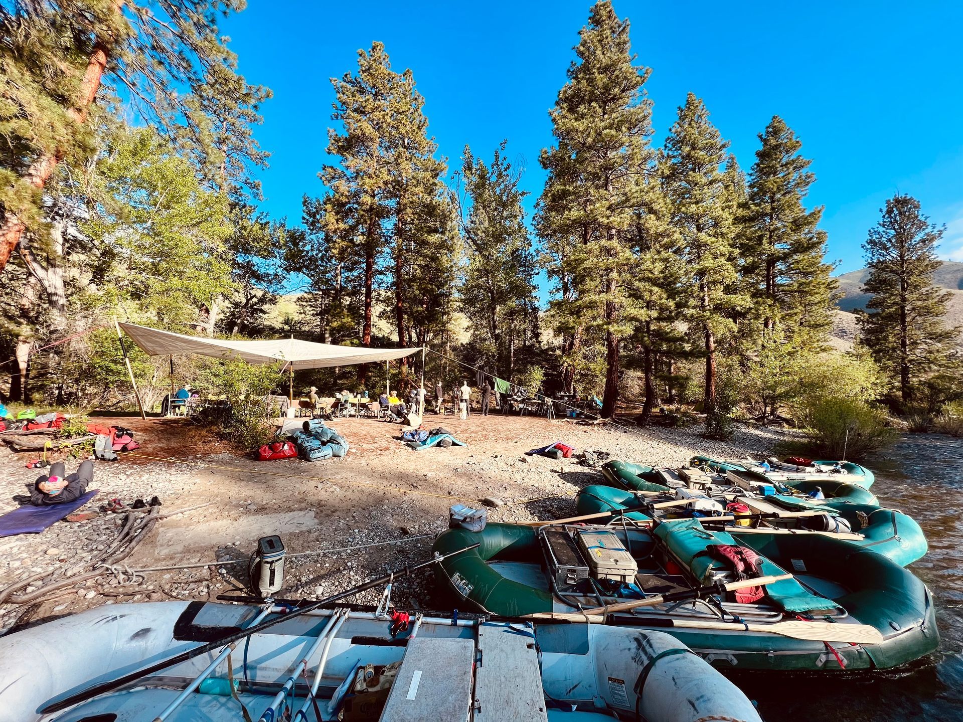 A group of rafts are sitting on the shore of a river.