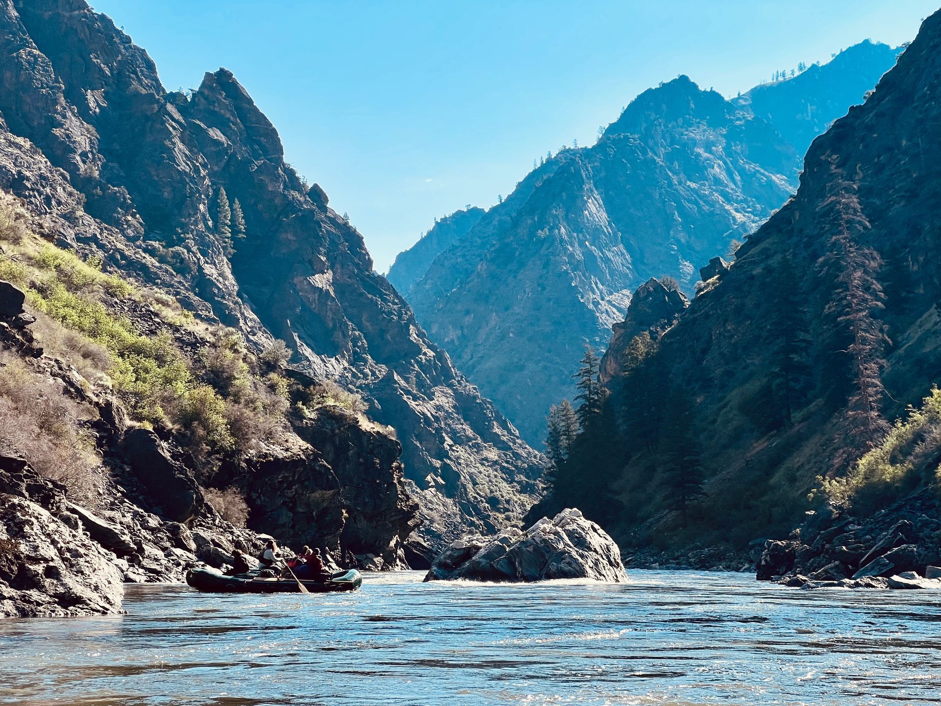 A river flowing through a canyon with mountains in the background