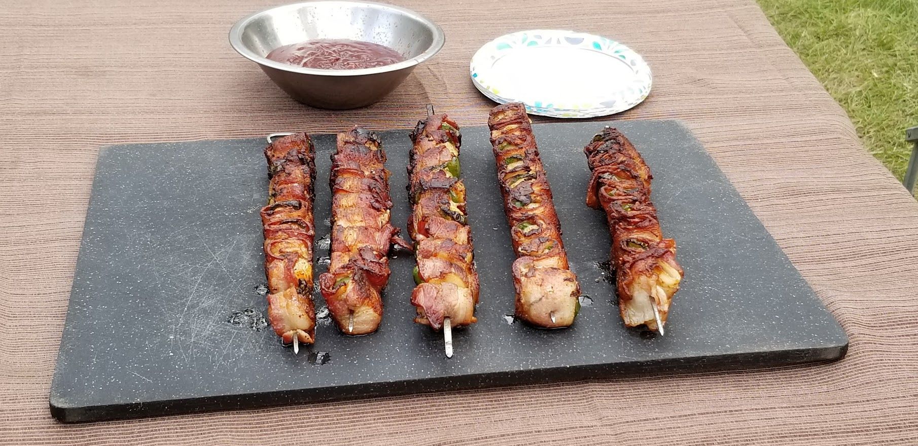 Four skewers of meat are sitting on a cutting board on a table.