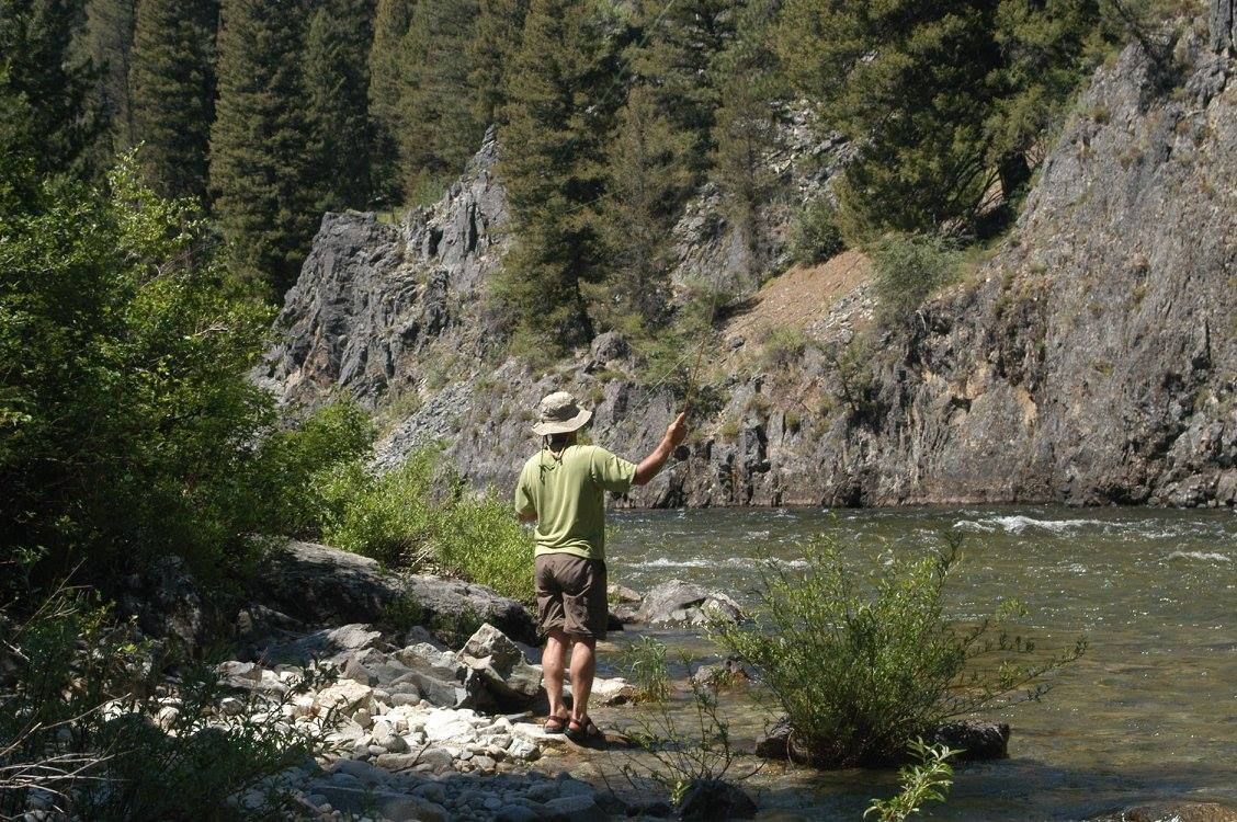 A man in a hat is fishing in a river.