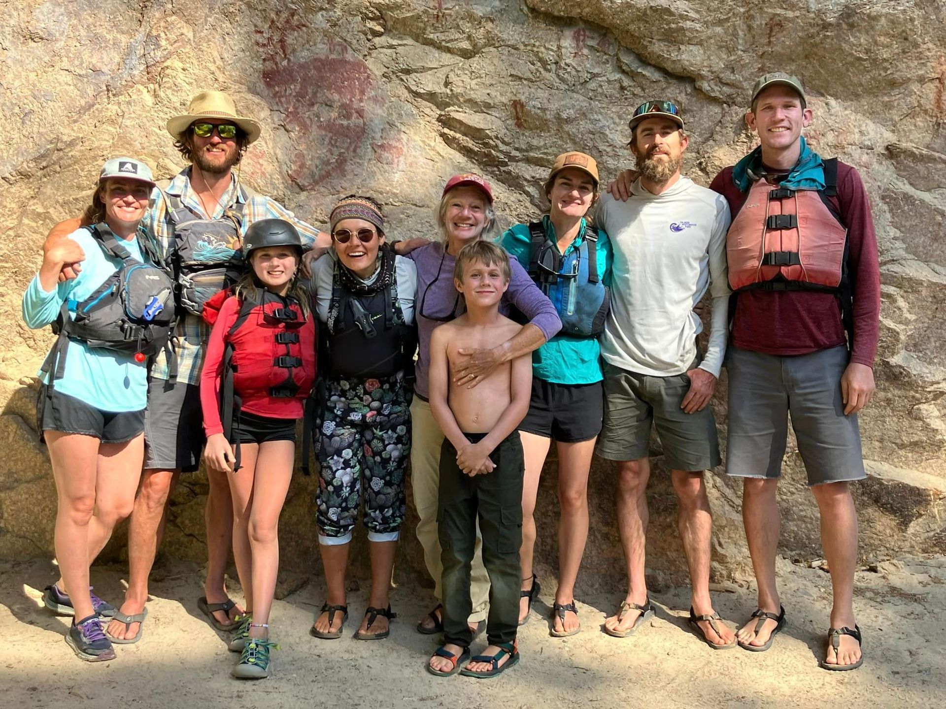 A group of people are posing for a picture in front of a rock wall.