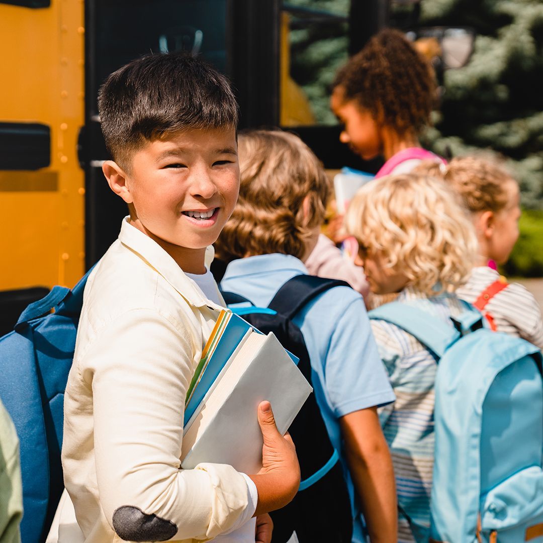 A group of children are standing in front of a school bus.