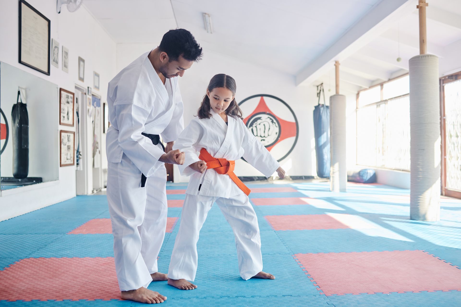 A man and a girl are practicing karate in a gym.