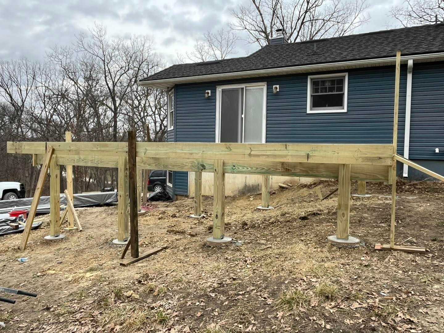 Deck construction underway; wooden frame raised on concrete piers, attached 