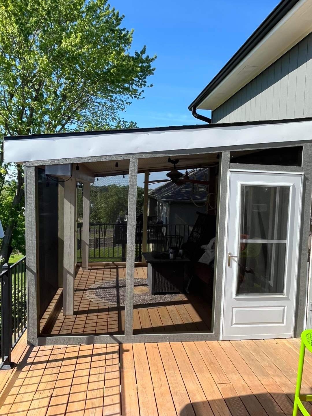 Screened-in porch with a wooden deck. Grey framing and screen walls surround 