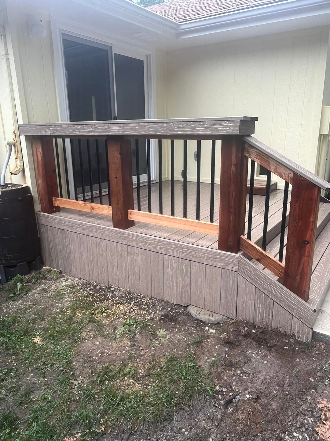 A partially built deck with composite decking and a wooden railing with black 