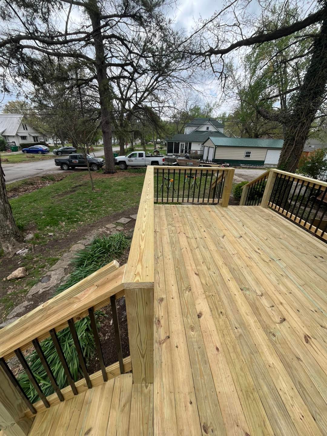 A newly built wooden deck with black railings. A staircase leads down to a yard 