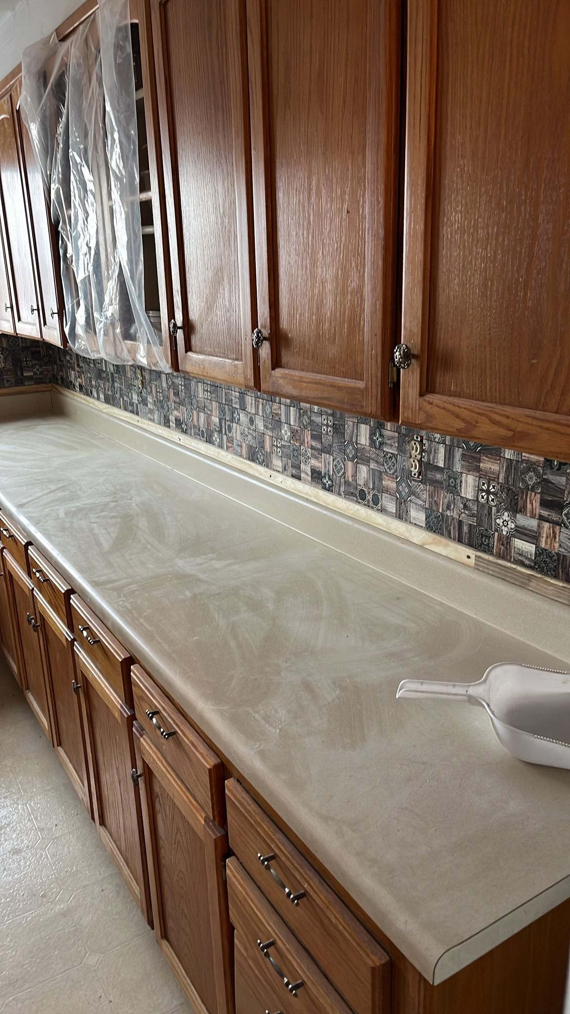 Kitchen with light-colored countertops, wooden cabinets, and a tiled 