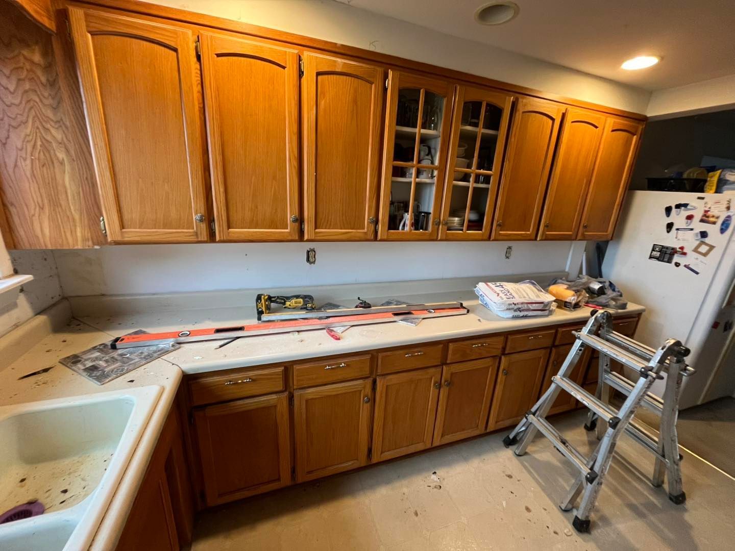Kitchen with light brown cabinets, a white countertop, and a ladder. 