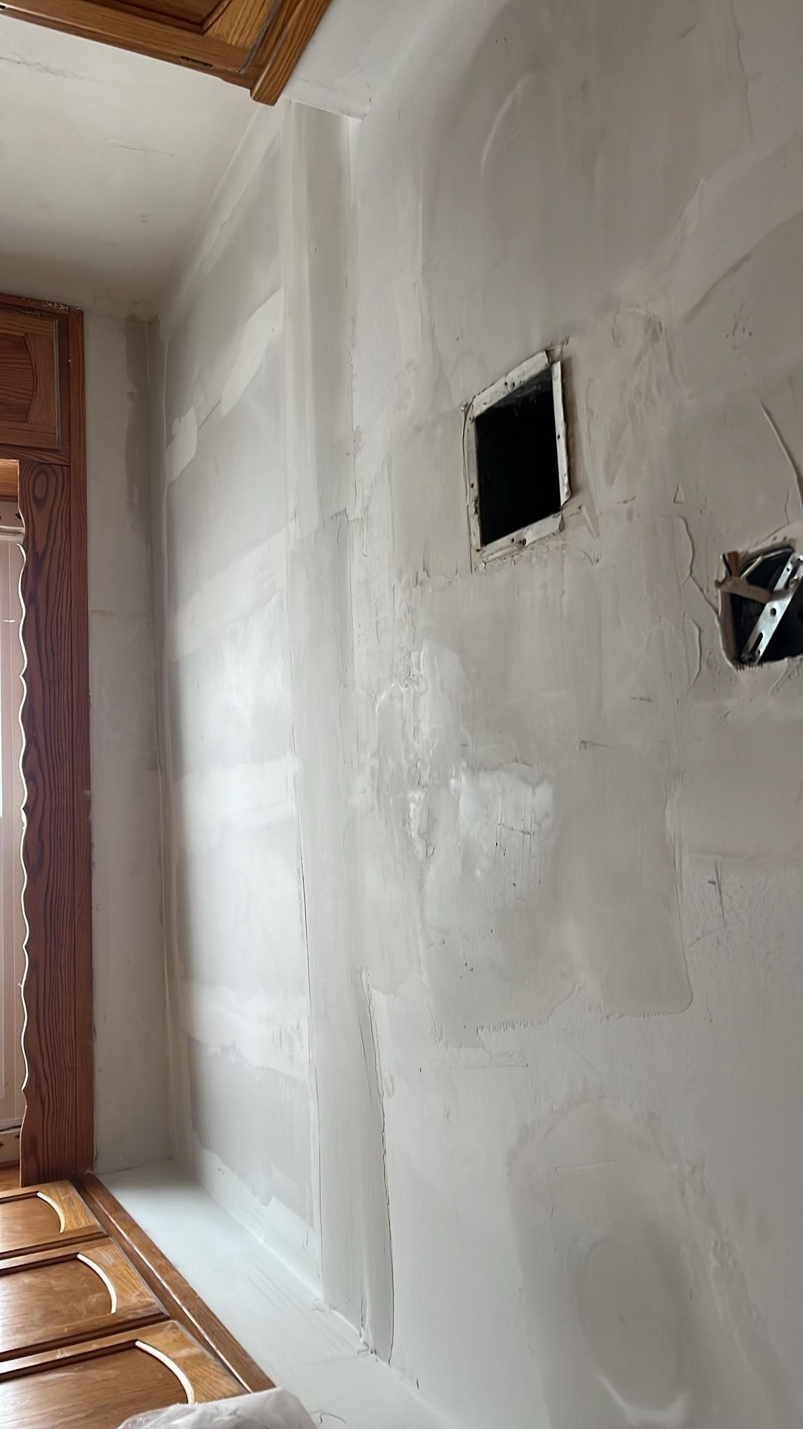 Interior wall in progress with white primer, electrical boxes, and a black vent.