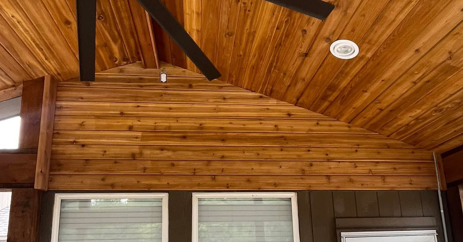 Wooden ceiling with dark beams and recessed lighting above windows with closed blinds.