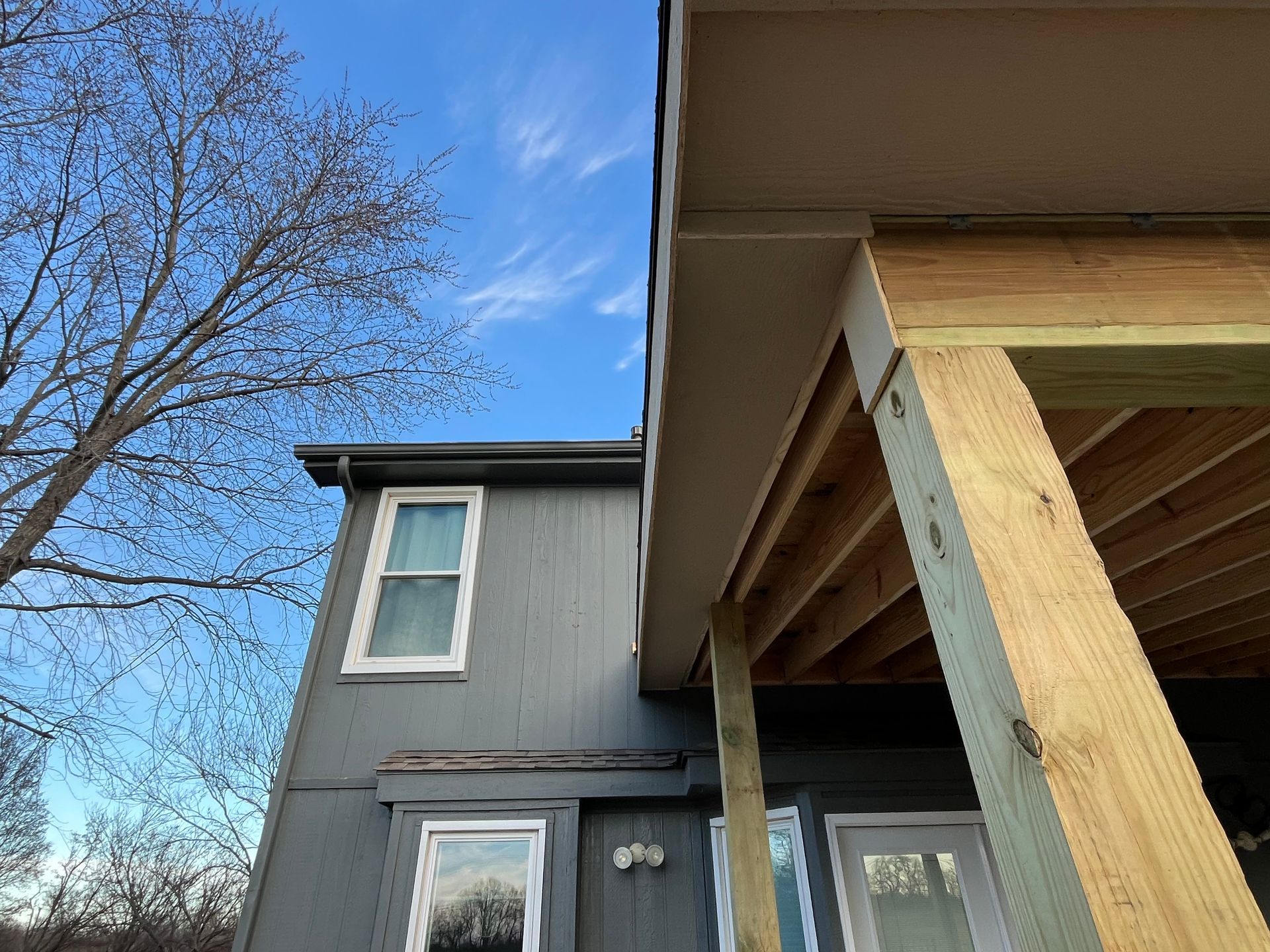 Exterior view of a house with a newly constructed wooden deck under a blue sky.