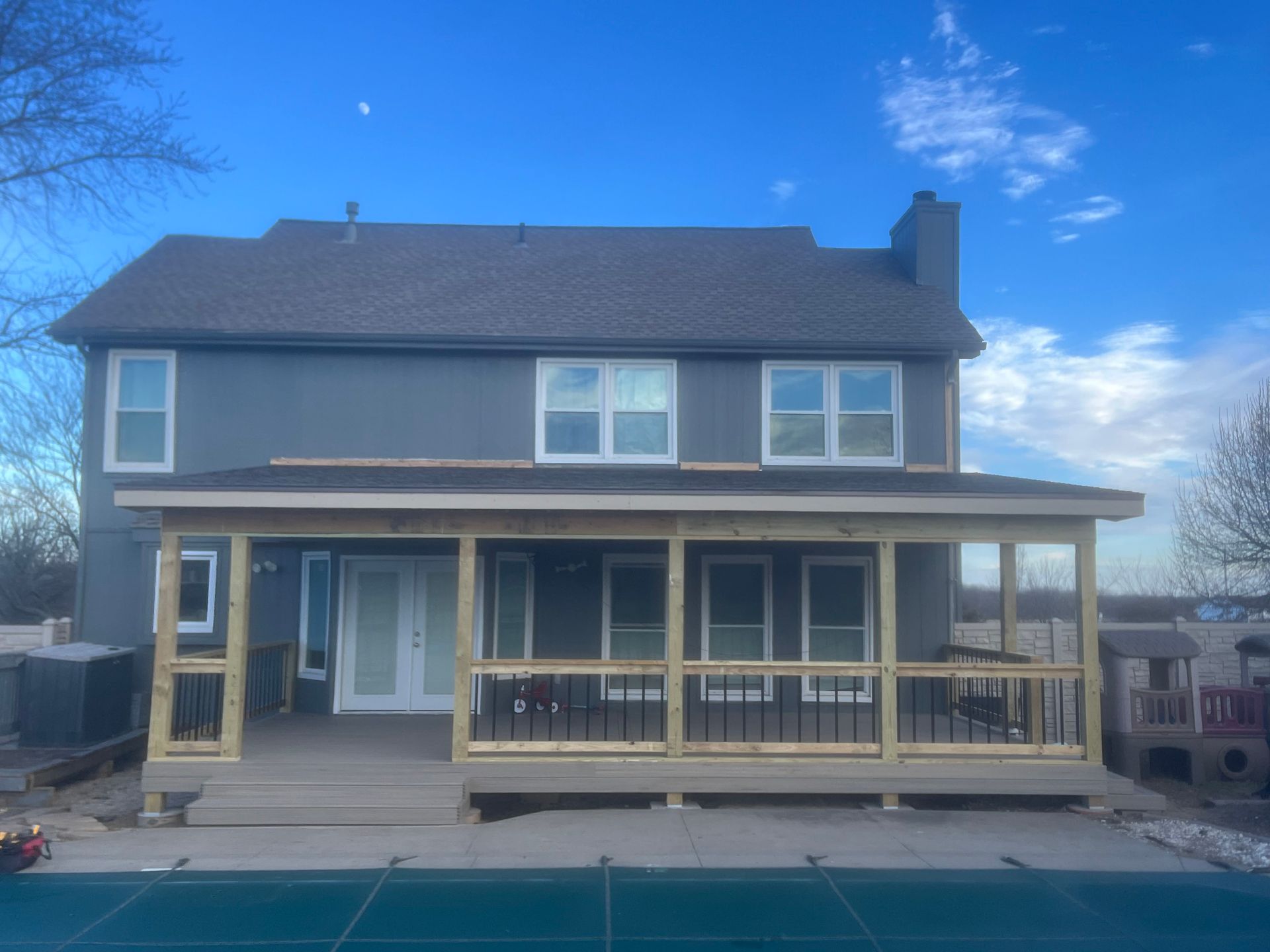 Back of a gray two-story house with a newly built screened porch and a swimming pool in the foreground.