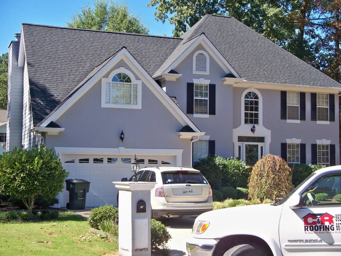 A white car is parked in front of a large house