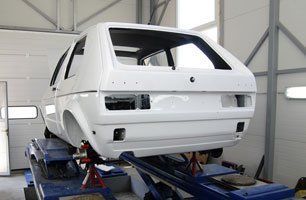 A white car is sitting on a lift in a garage.