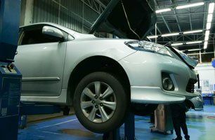 A silver car is sitting on a lift in a garage.