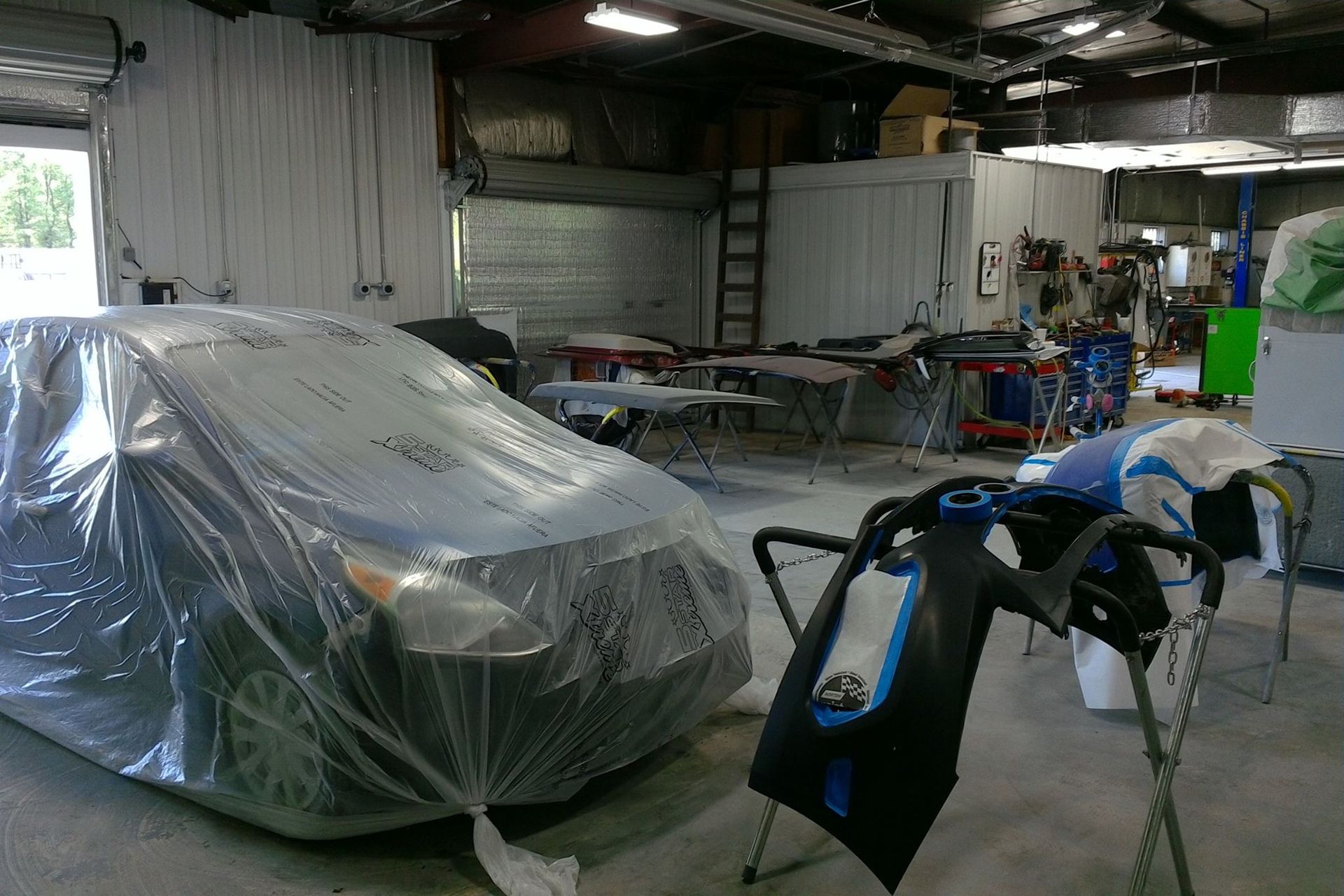 A car is covered in plastic in a garage.