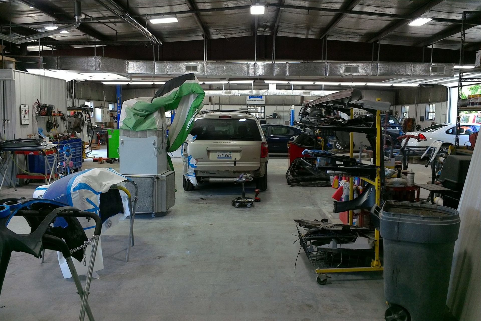 A car is being painted in a garage with other cars