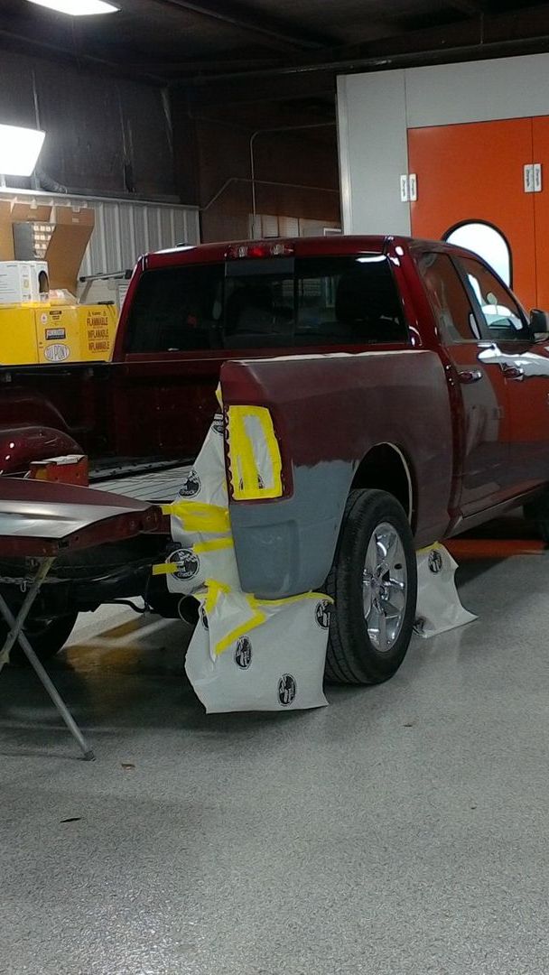 A red truck is being painted in a garage