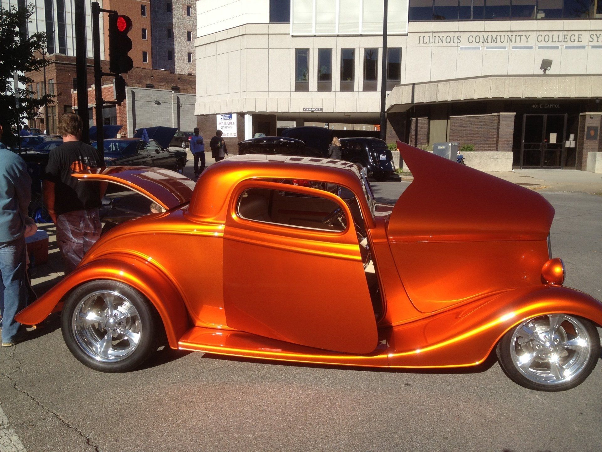 An orange car is parked in front of a building that says illinois community college