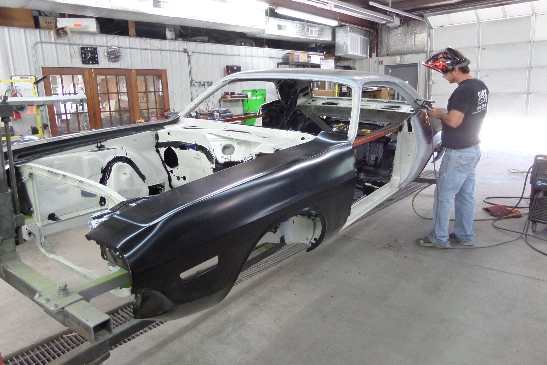 A man is welding a car in a garage.