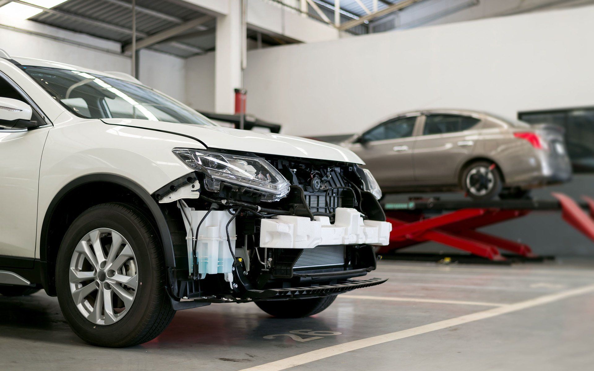 A white car is being repaired in a garage.