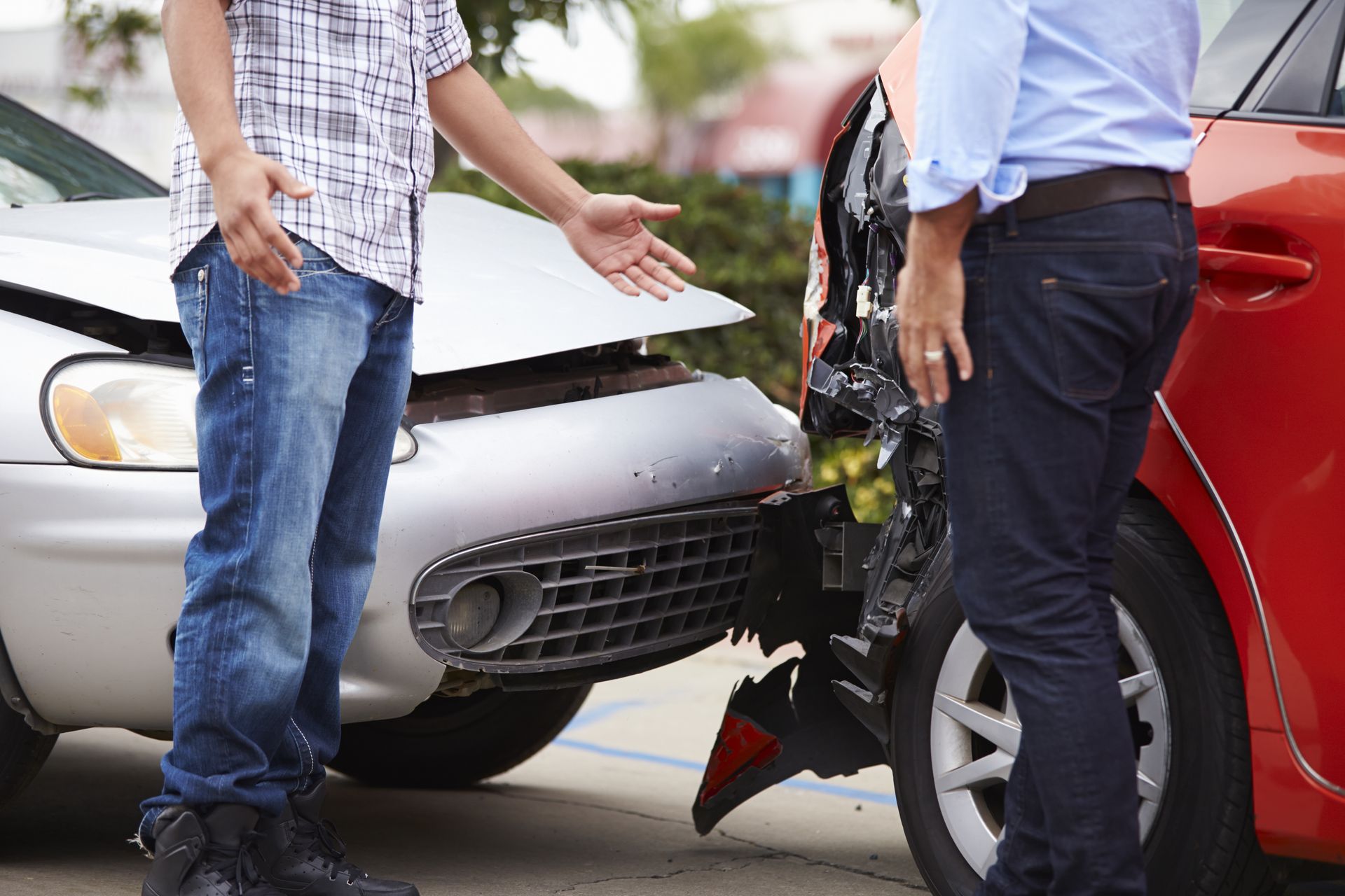 Two men are standing next to a car that has been involved in a car accident.