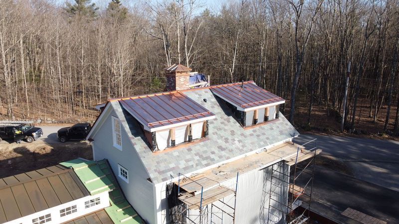 Close-up of a brown tiled roof against a blue sky with white clouds.