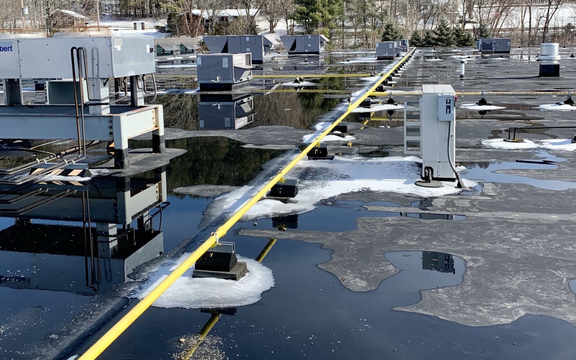 Flat, gray roof with a vent, overlooking a town, mountains, and blue sky. Flat, gray roof with a vent, overlooking a town, mountains, and blue sky.