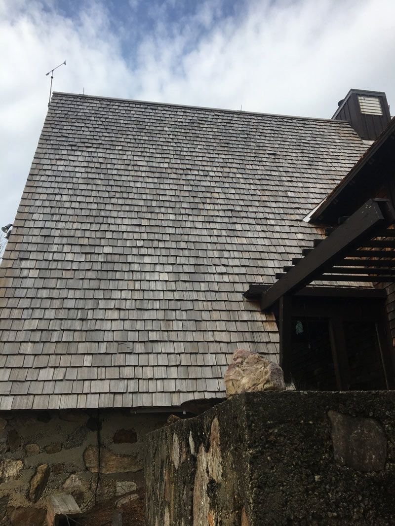 Wooden shingle roof on a building, a partial view, against a cloudy sky. Wooden shingle roof on a building, a partial view, against a cloudy sky.