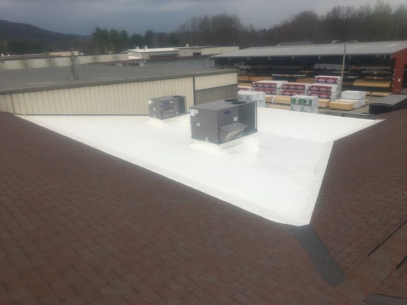 Commercial building with brown shingle roof and white flat roof, featuring HVAC units.