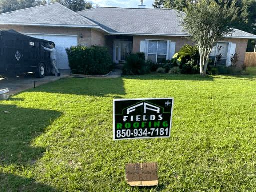 Front yard sign for Fields Roofing on a suburban lawn in front of a house
