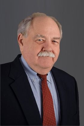 A man with a mustache is wearing a suit and tie