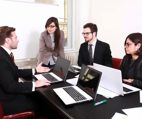A group of attorneys are sitting around a table with laptops.