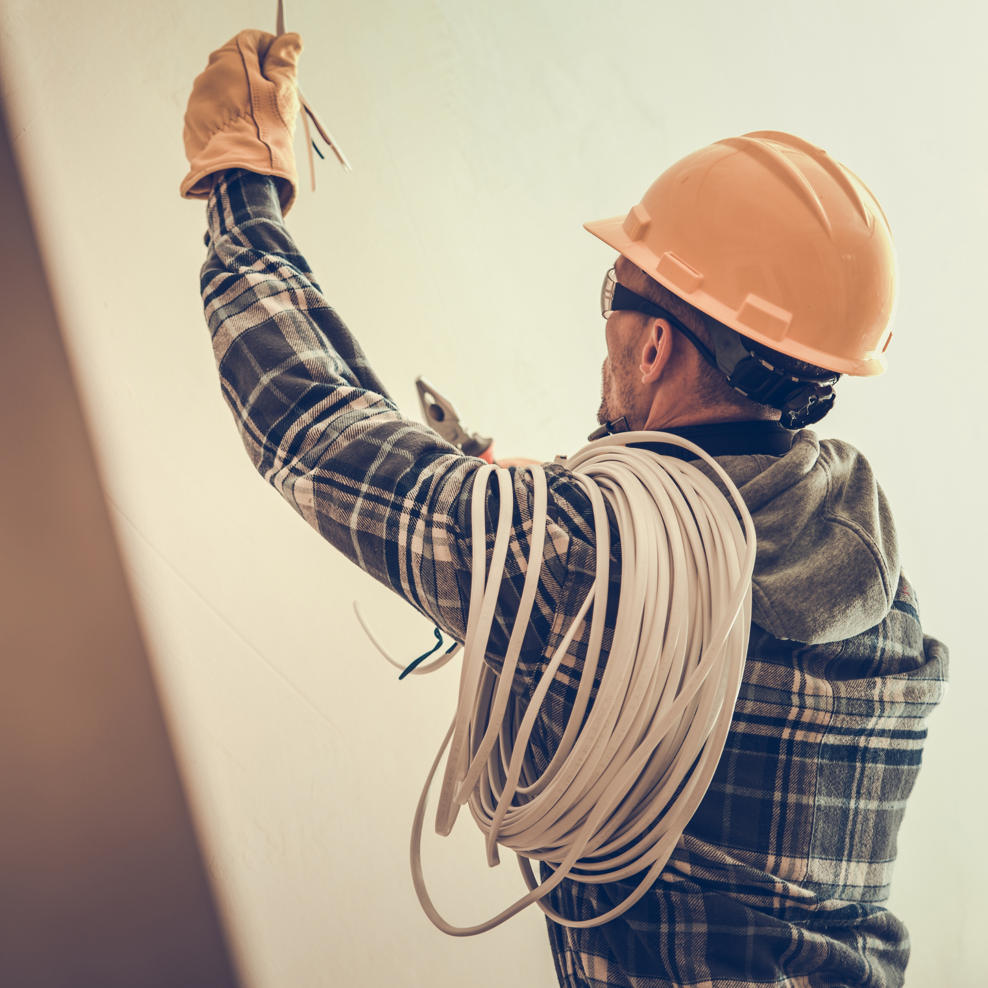 Electrician in a hard hat working with wires.