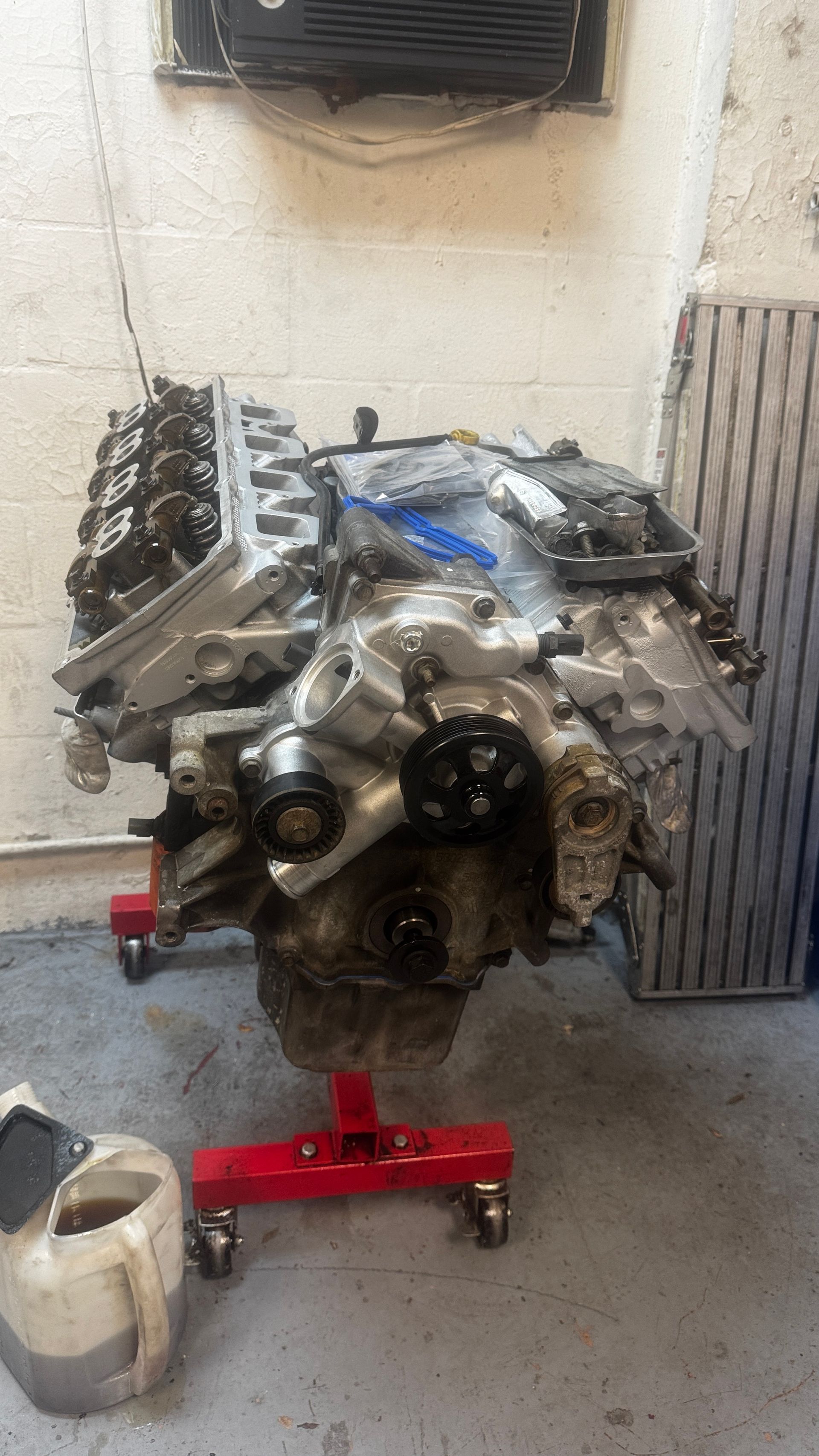 A partially disassembled V8 engine on a red metal engine stand in a workshop.