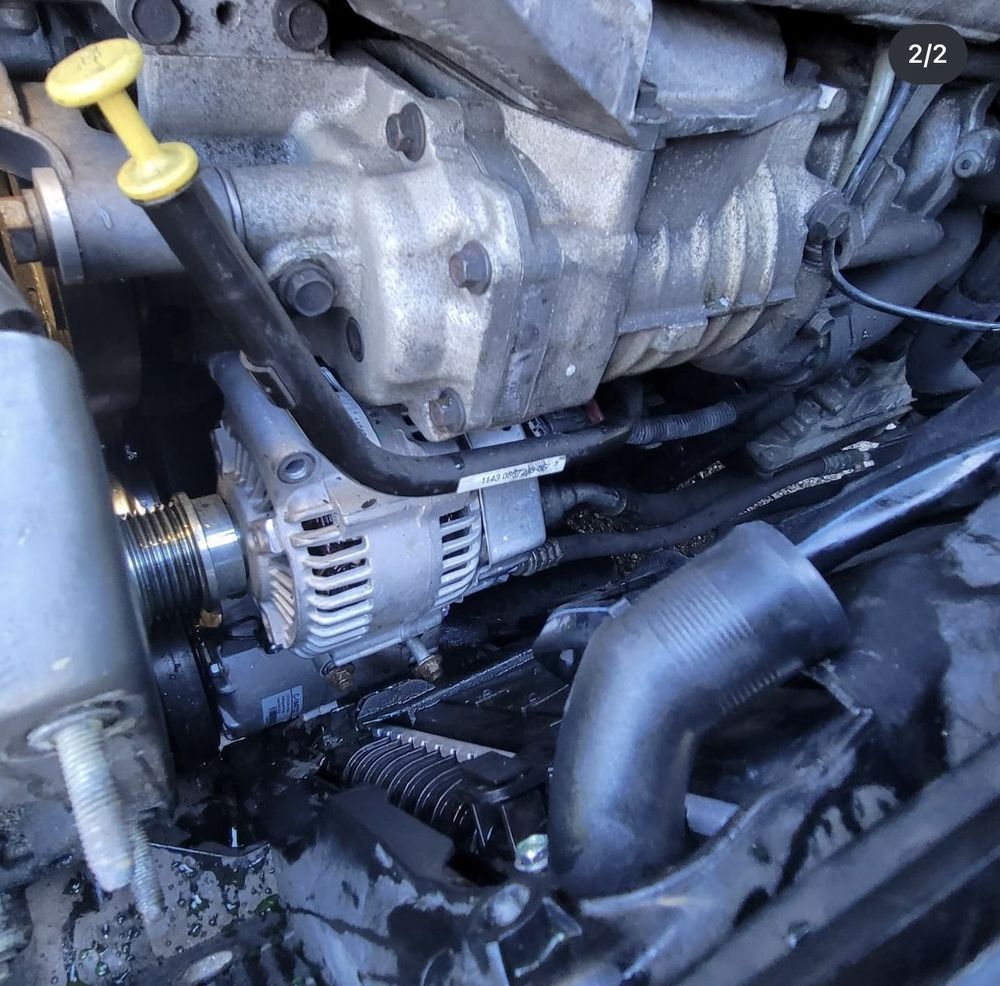 Engine compartment showing an alternator, belts, and hoses.