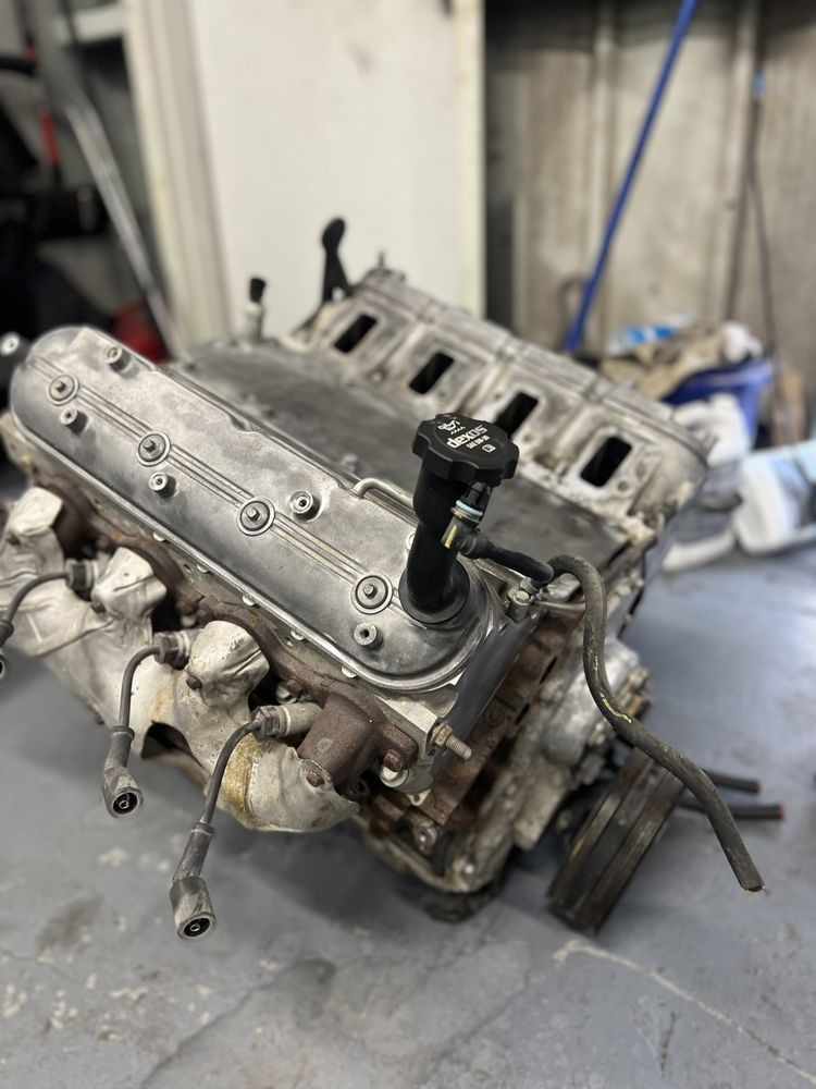 Gray engine block with cylinder heads, spark plugs, and oil cap.
