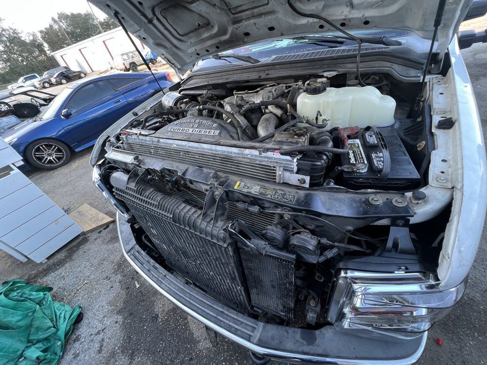 Truck engine compartment open, showing radiator, battery, and engine components.