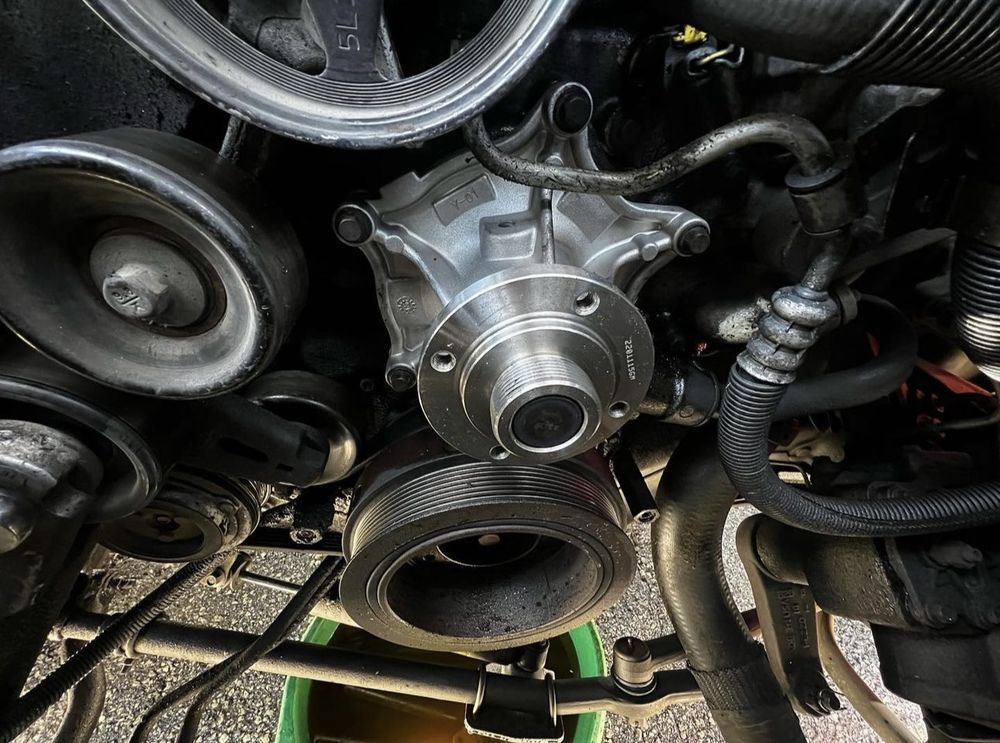 Engine water pump with pulley and belt system, in an automotive setting.