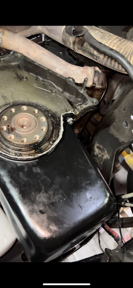 Engine component, likely a fuel tank, with a visible damaged edge. Dark, metallic color.