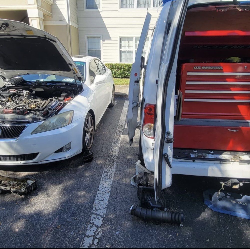 White car with open hood next to a work van. Tools visible, possibly a roadside repair.